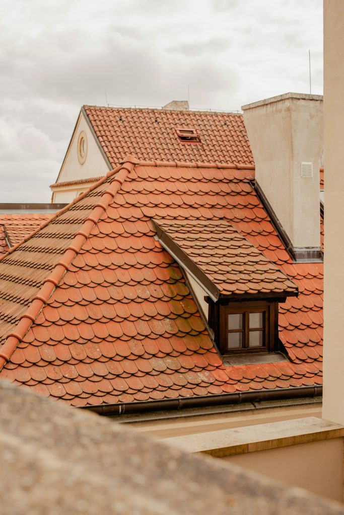 un toit de tuiles rouges avec une tour d'horloge en arrière-plan
